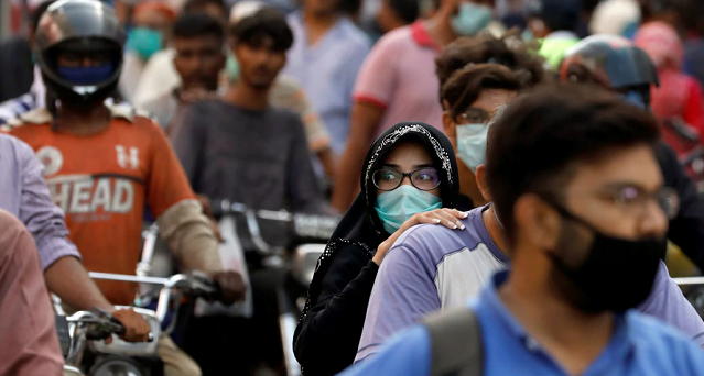 a woman wears a face mask as she sits at the back of a motorcycle on a street in karachi pakistan photo reuters file