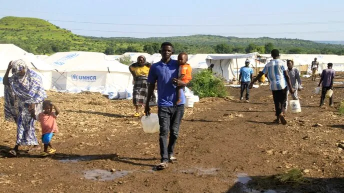 Displaced Sudanese who have returned from Ethiopia, carry gallons of water in a camp run by the United Nations Refugee Agency (UNHCR) in Sudan