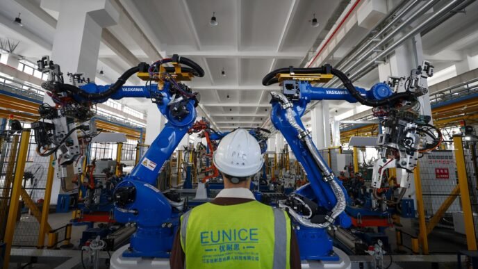 A worker inspects the operation of robotic arms in a factory in Jiangdu district, Yangzhou, East China