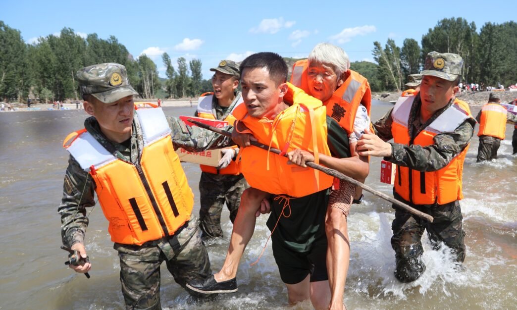 Armed Police Force carry a local resident to safety during a flood in Huludao city in Liaoning Province on August 23, 2024. Photo: VCG